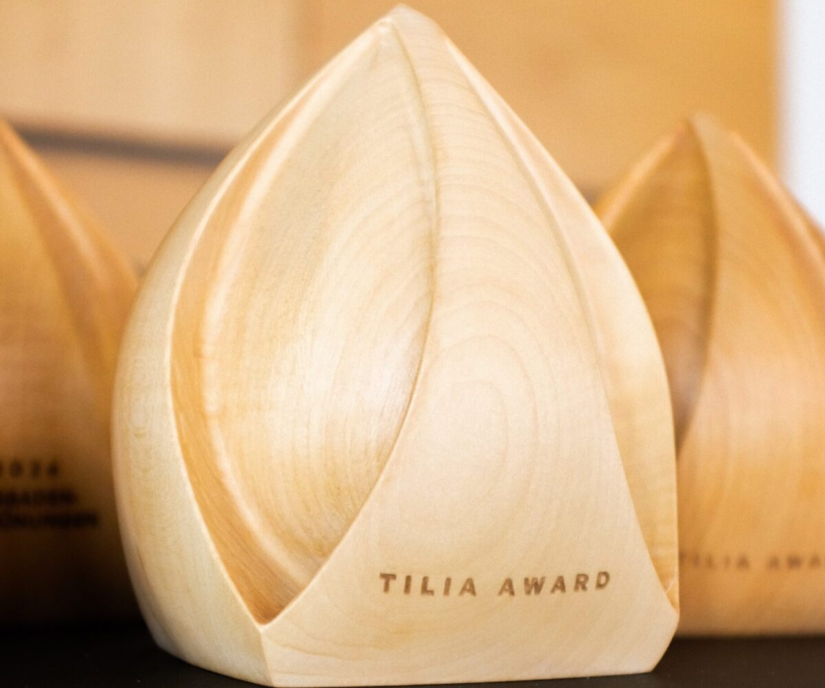 Holztrophäen in Form einer Blüte mit der Gravur "TILIA AWARD" auf der Vorderseite.